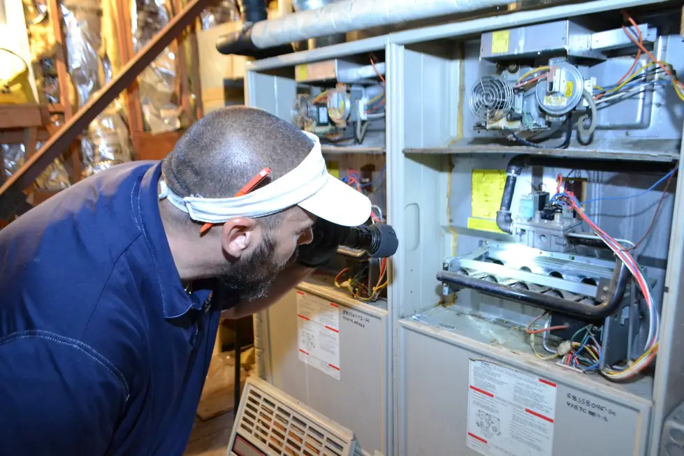 Trevor Battieste reading a residential furnace with a handheld thermal imaging camera